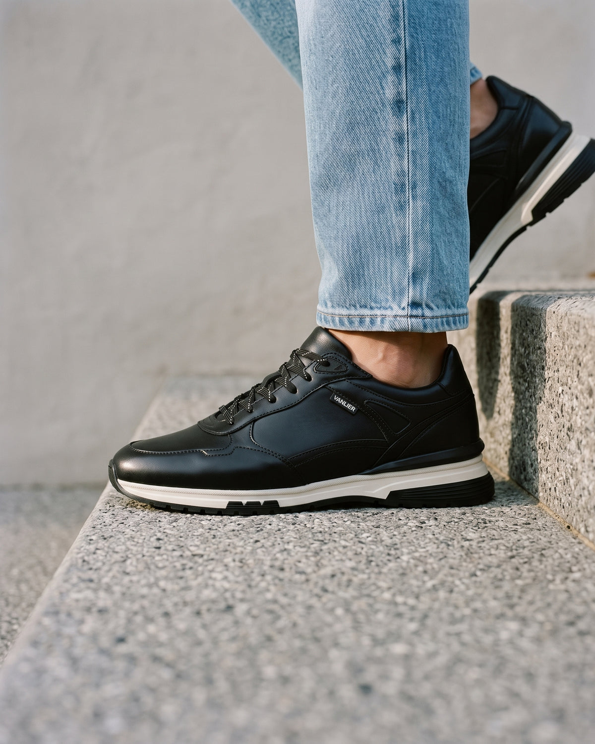 Zwart gladleren Veneto sneaker – close-up van het paar in een betonnen atelier