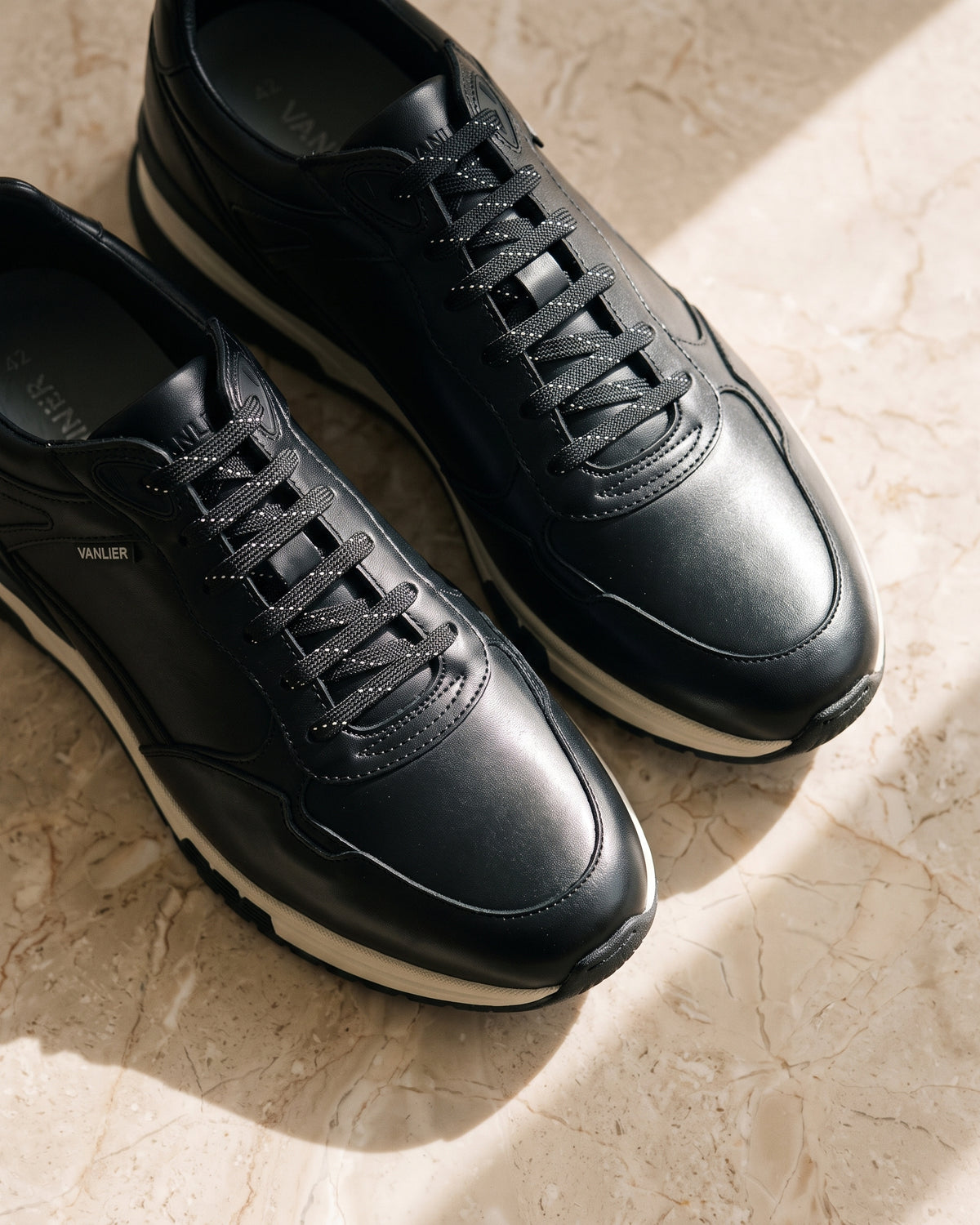 Zwart gladleren Veneto sneaker – detail van het paar op marmer