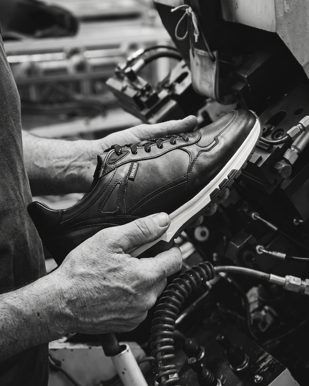 Zwart gladleren Veneto sneaker – vakmanschap, schoen vastgehouden in de werkplaats