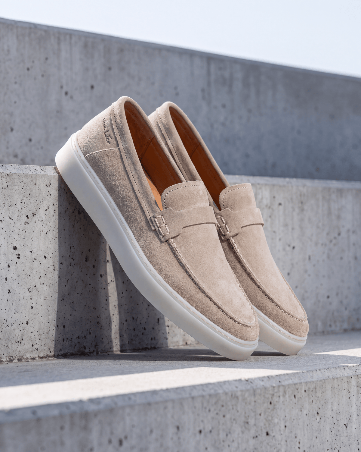 Beige suède Bari loafer – het paar op ruw beton