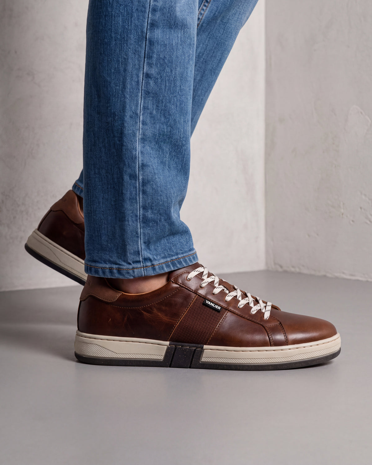 Cognac gladleren Retro sneaker – close-up van het paar in een betonnen atelier