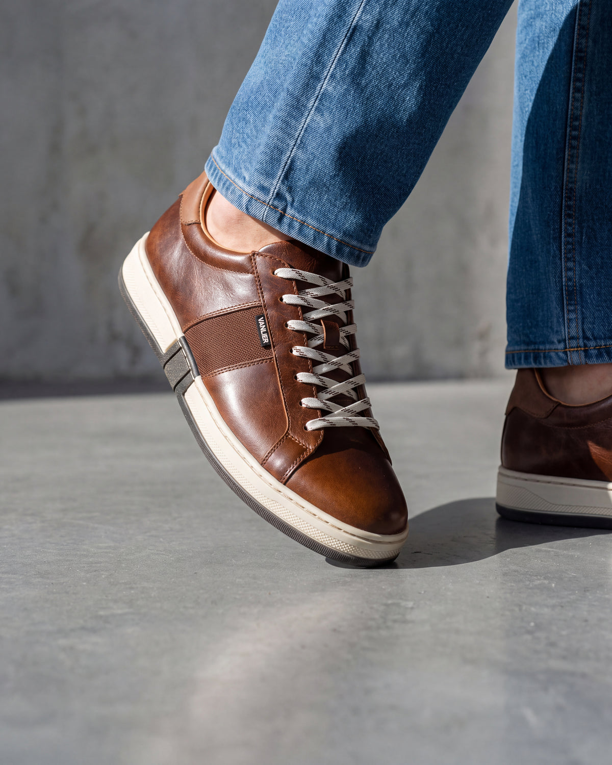Cognac gladleren Retro sneaker – close-up van het paar op een ruwe betonnen vloer