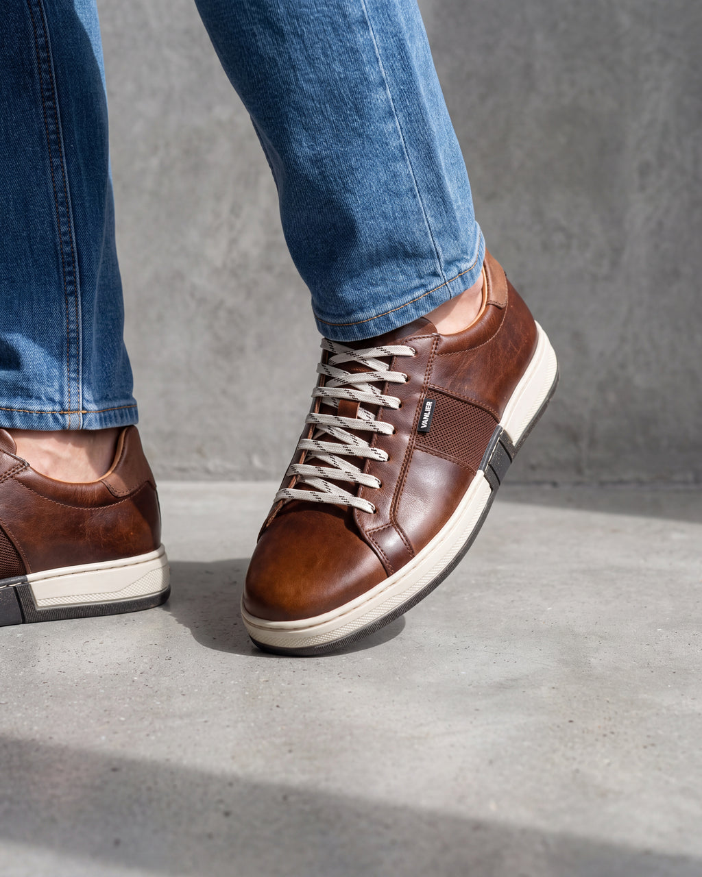 Cognac gladleren Retro sneaker – close-up van het paar op een ruwe betonnen vloer, andere hoek