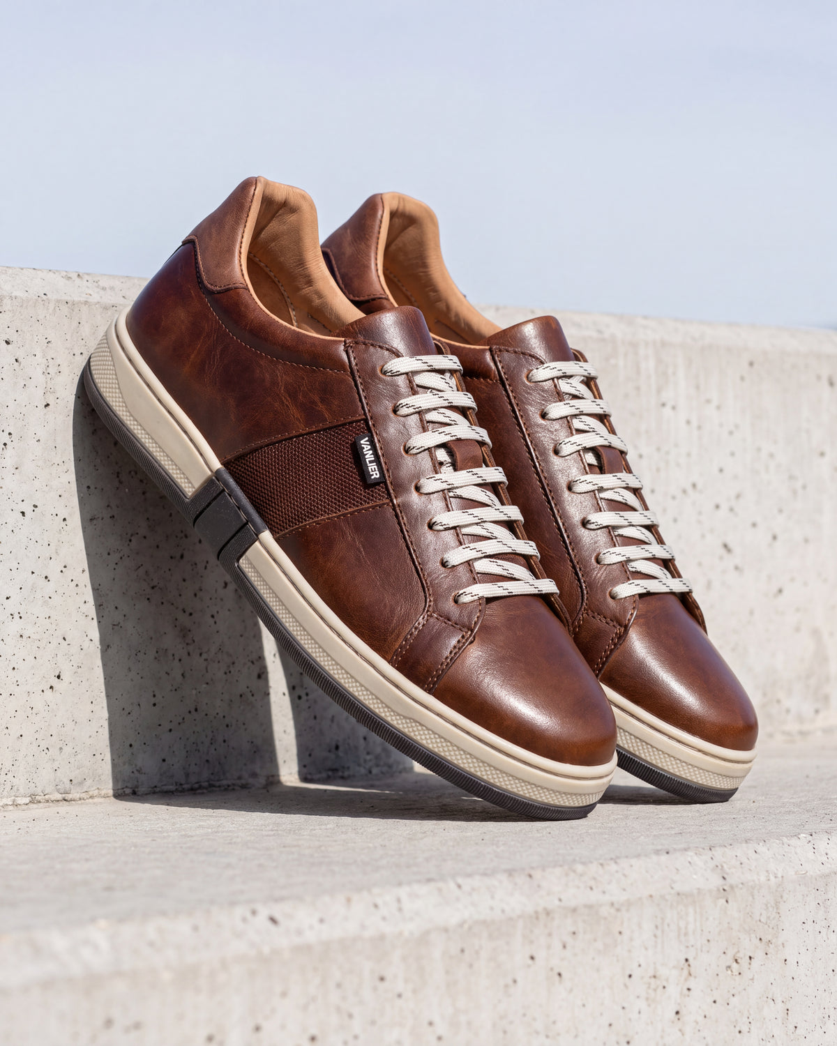 Cognac gladleren Retro sneaker – detail van het paar op ruw beton, andere hoek