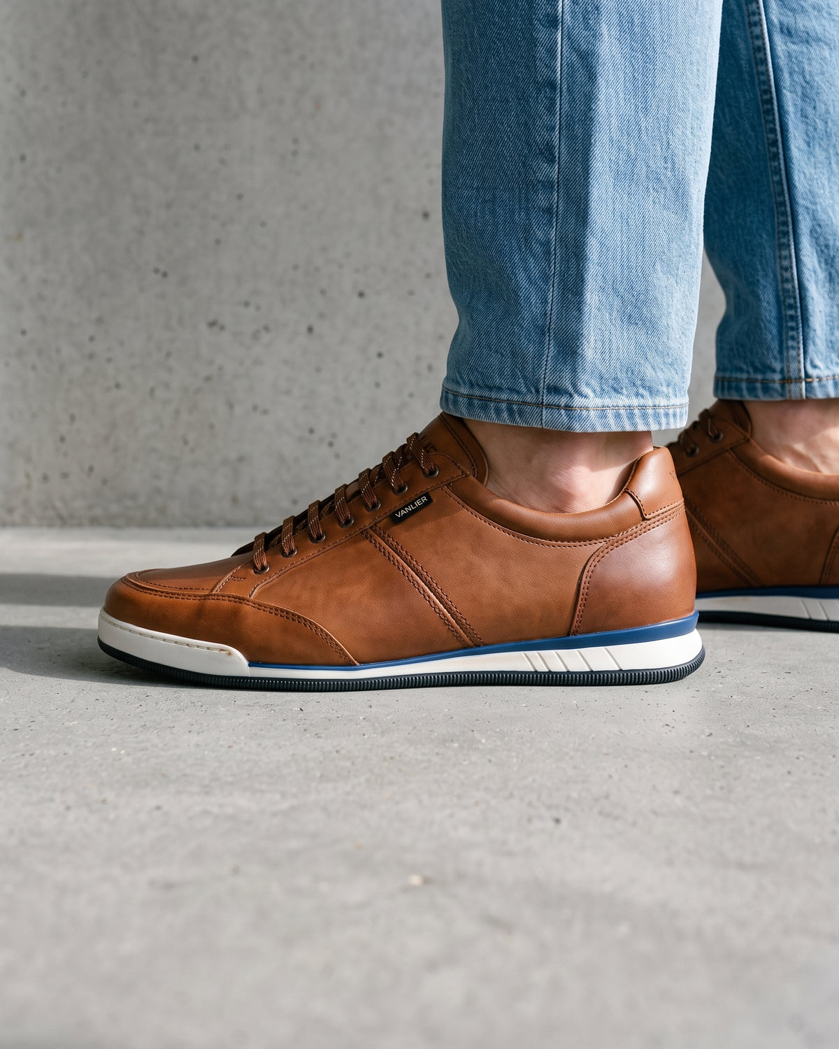 Cognac gladleren Magnus sneaker – close-up van het paar op een betonnen vloer, andere hoek