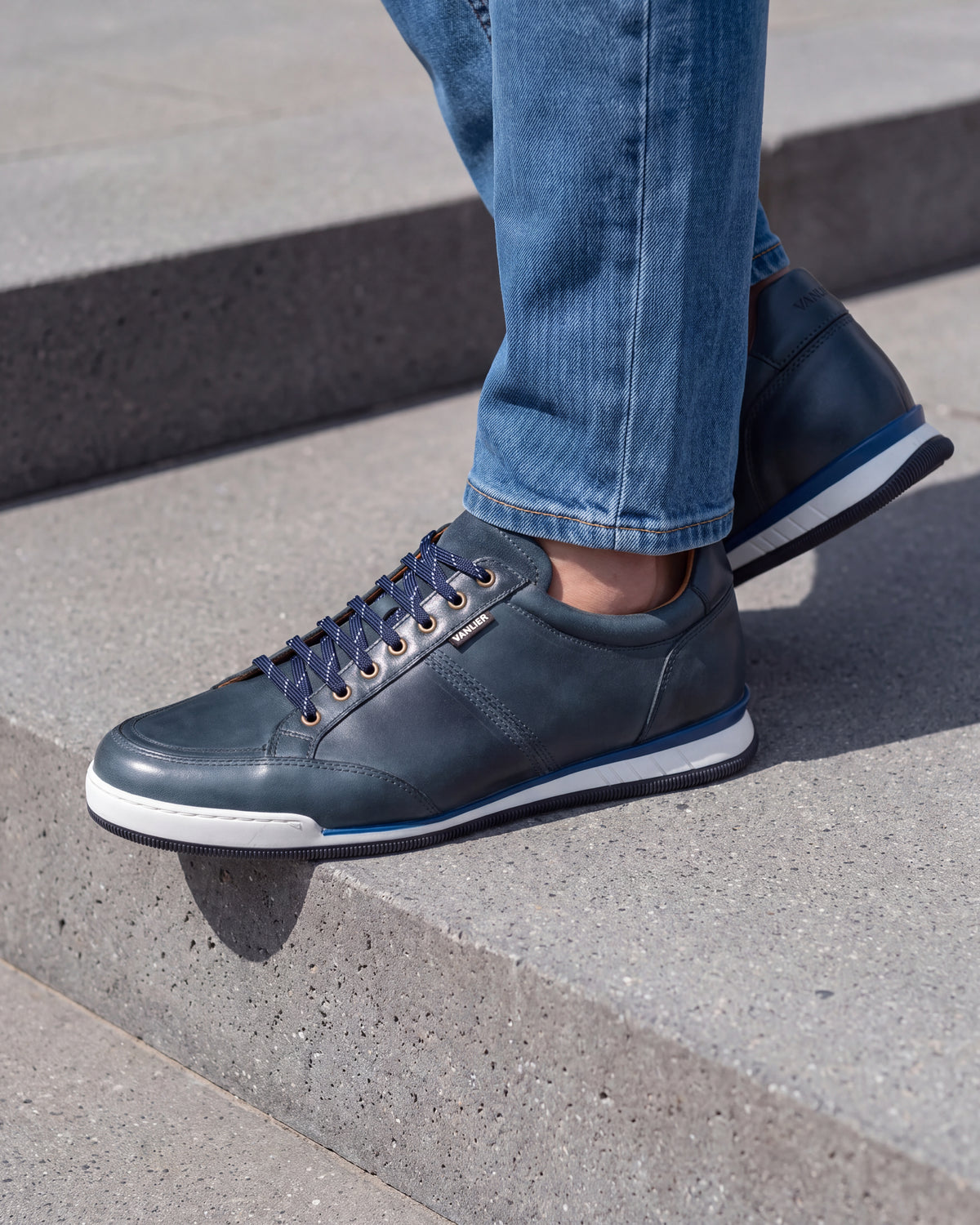 Blauw gladleren Magnus sneaker – close-up van het paar op een betonnen vloer