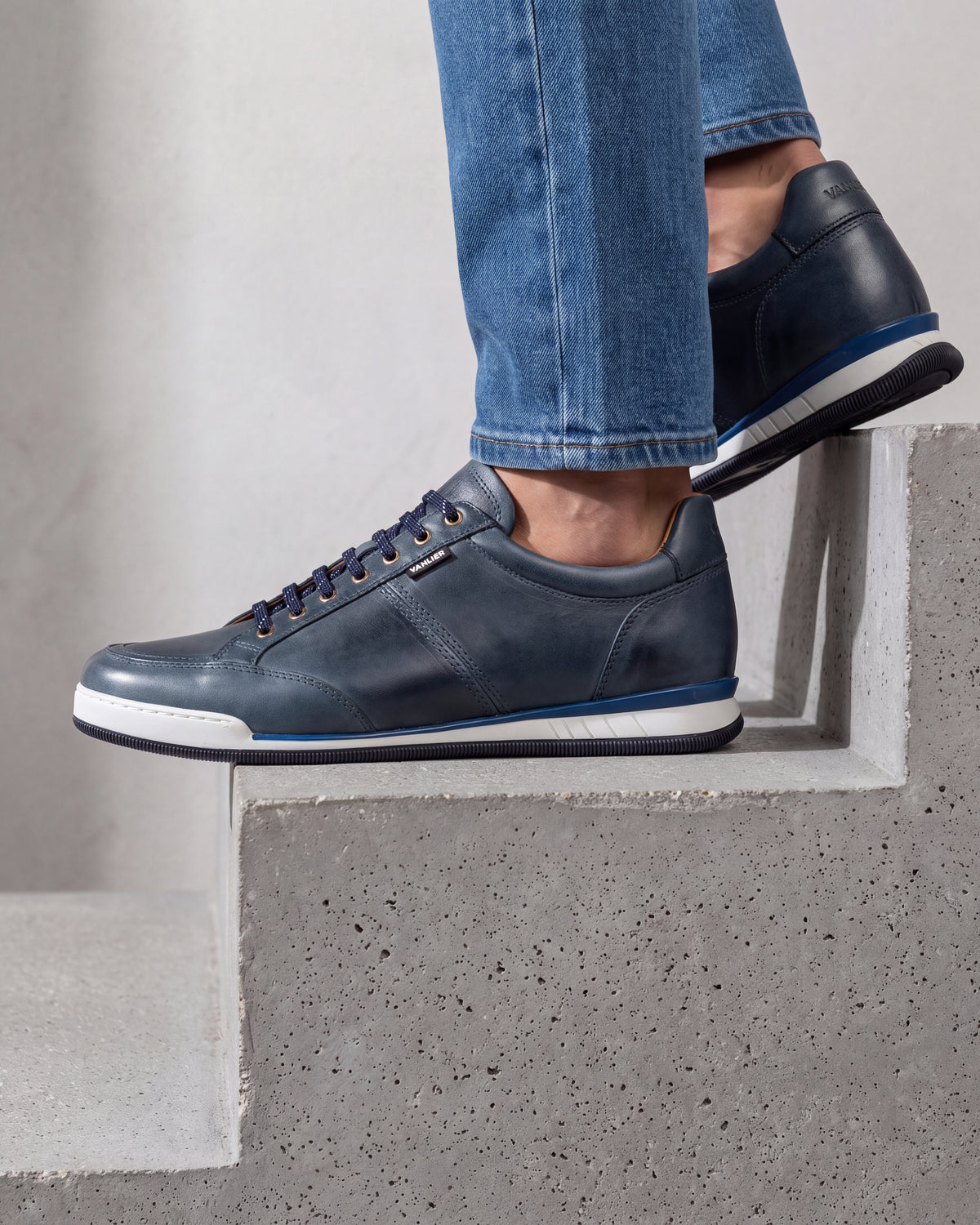 Blauw gladleren Magnus sneaker – close-up van het paar in een betonnen atelier