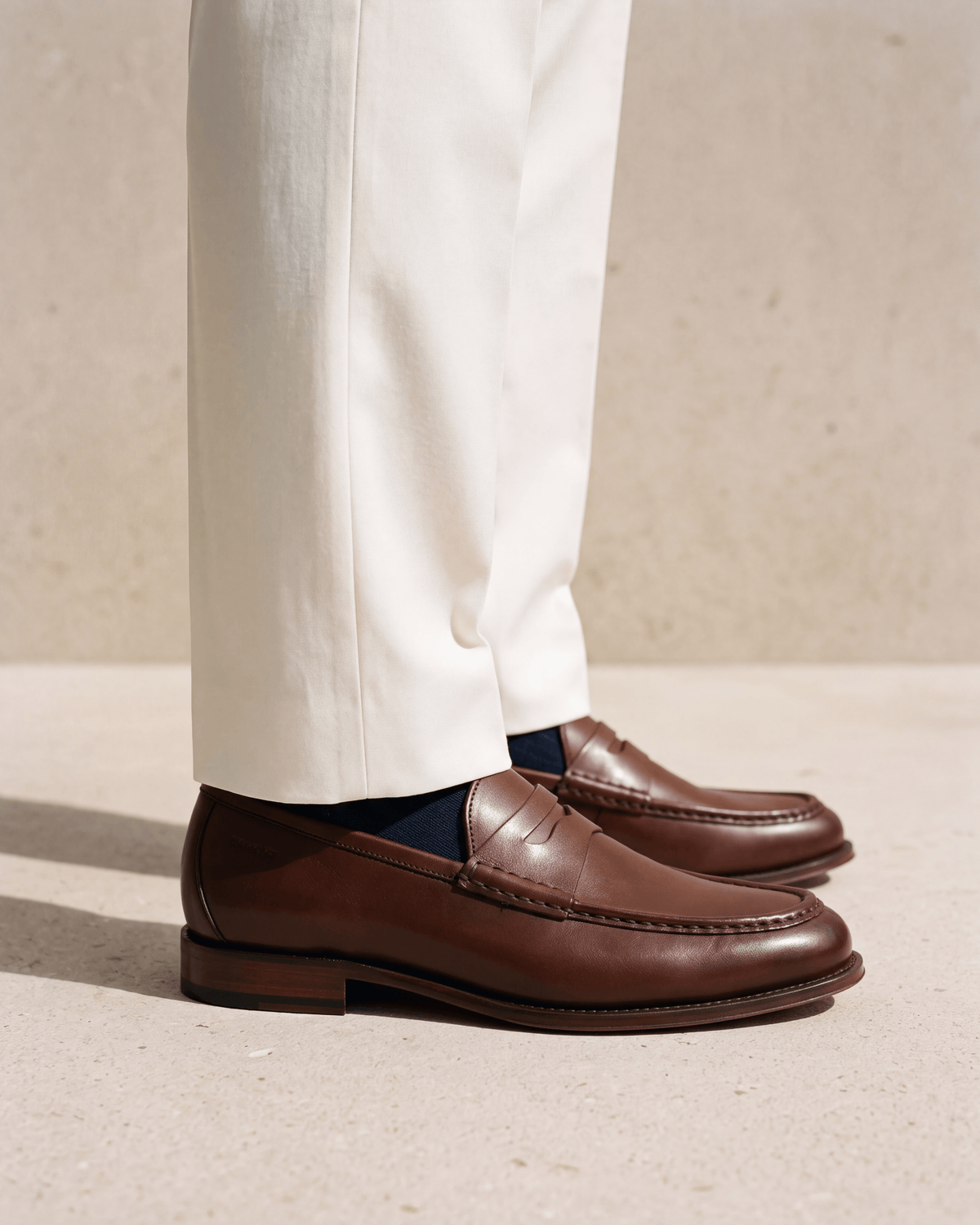 Cognac gladleren Cambridge Penny loafer – close-up van het paar op een kalkstenen vloer