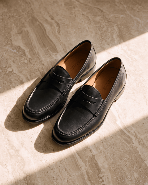 Zwart gladleren Cambridge Penny loafer – close-up van het paar op steen in de zon