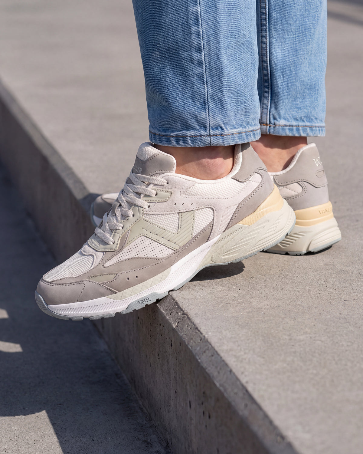 Wit lichtgroen combi Cosmos sneaker – close-up van het paar op een ruwe betonnen vloer