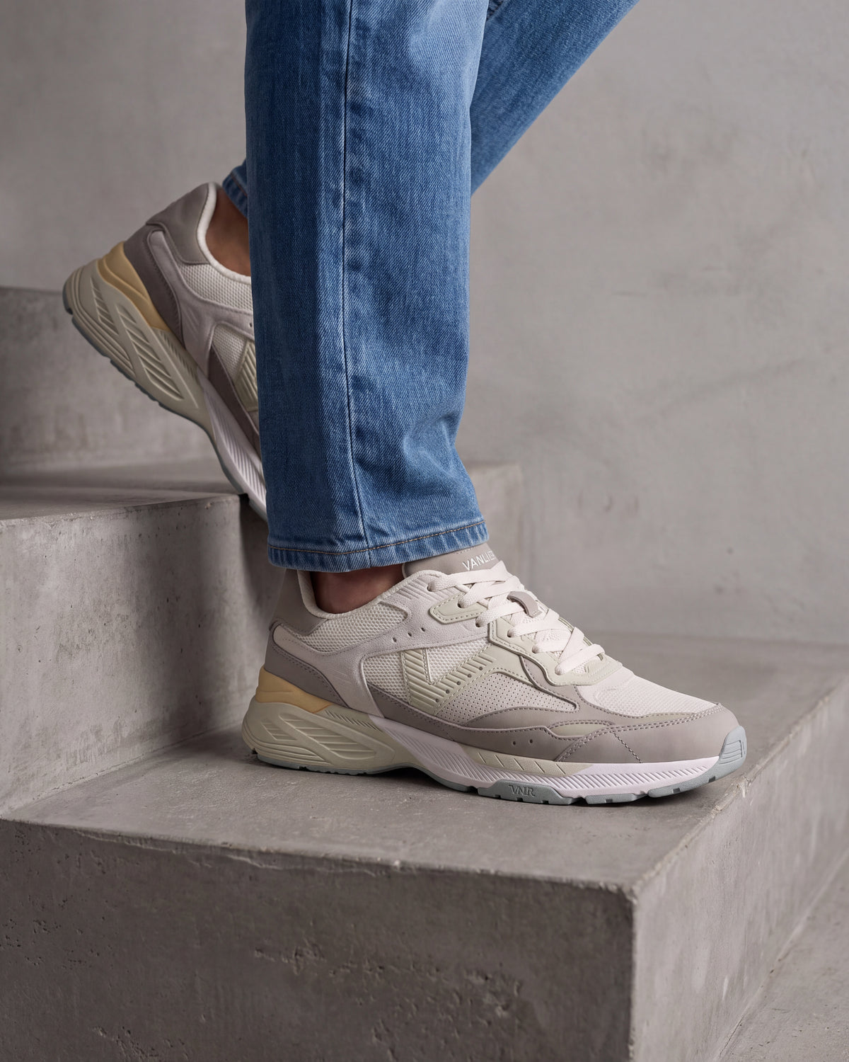 Wit lichtgroen combi Cosmos sneaker – close-up van het paar in een betonnen atelier