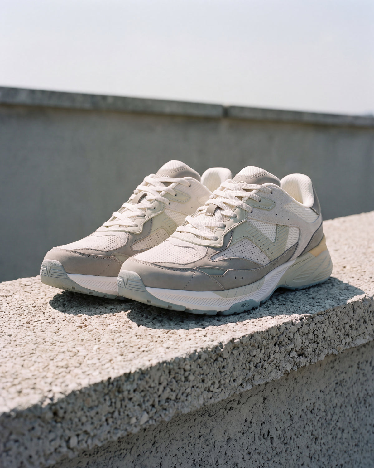 Wit lichtgroen combi Cosmos sneaker – close-up van het paar op ruw beton